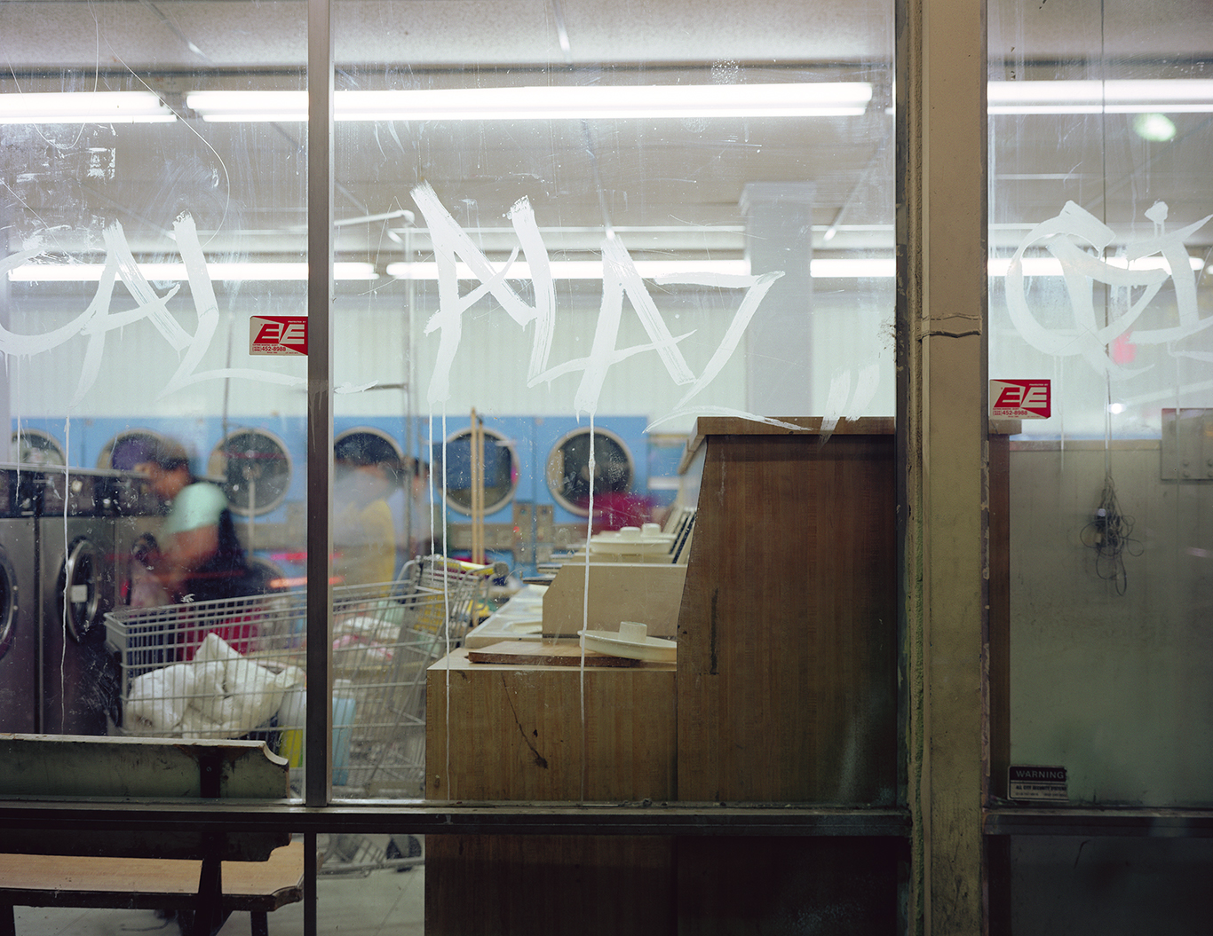 Detail of glass windows looking into laundromat with grafiti on window